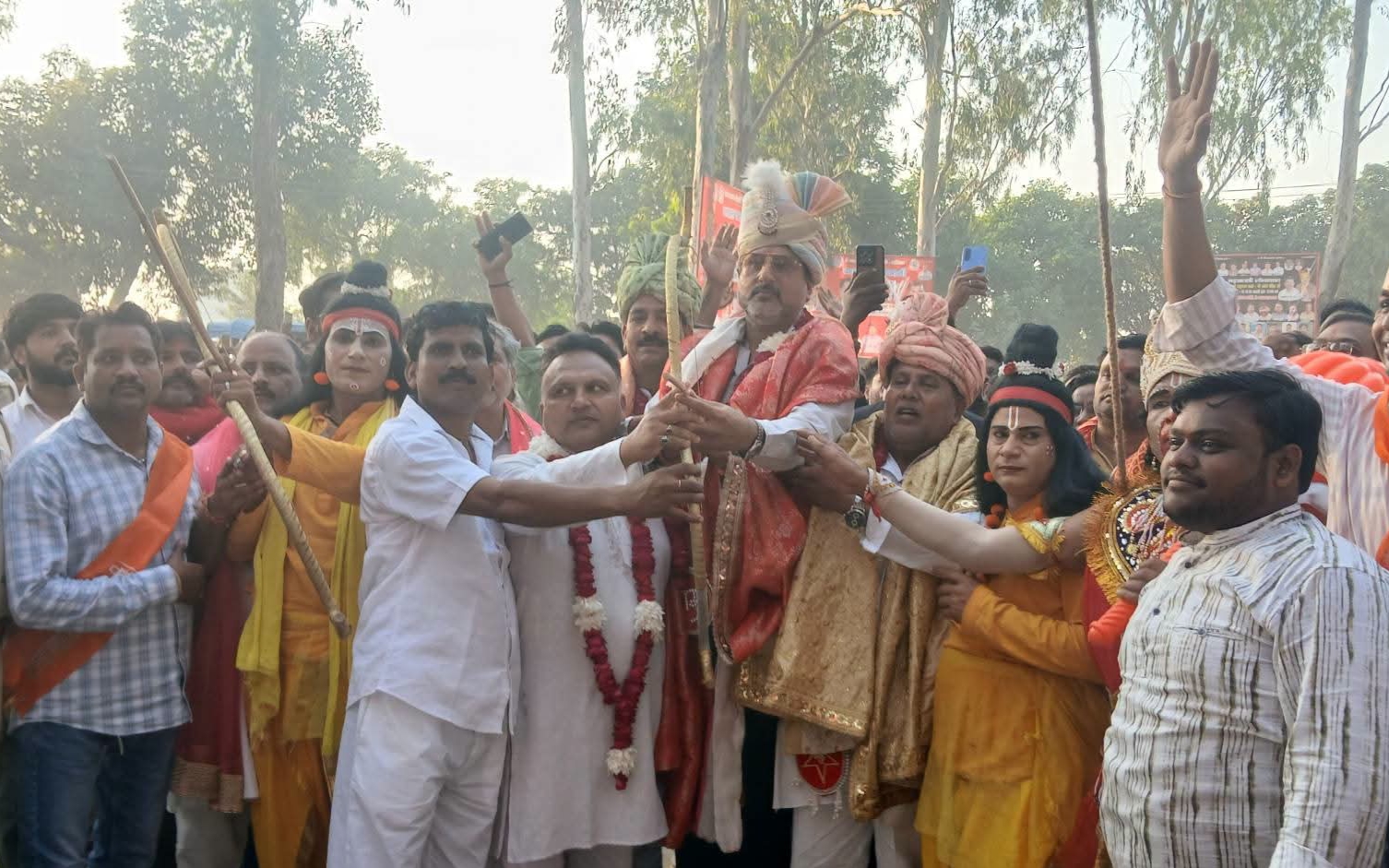 Participants holding a bow beside costumed performers at the Jahangirabad Ramlila gathering