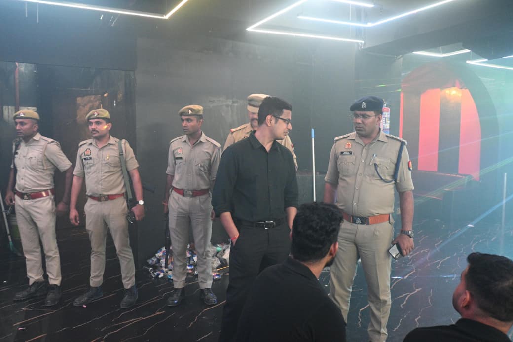 Police personnel and a man in dark clothing inside a dimly lit venue