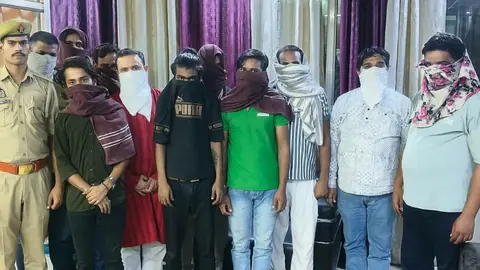 Group of adult men standing with a uniformed police officer, several with cloth coverings over their faces