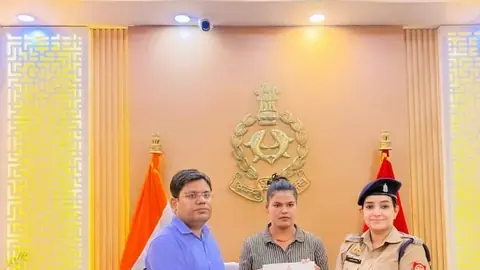 Three people hold a document behind an office desk, including a woman in khaki police uniform