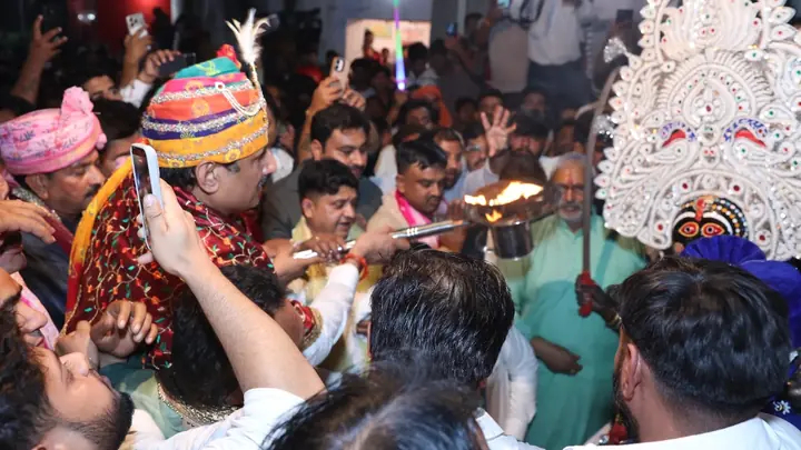 Crowd of devotees, a black-faced Kali-related representation and a flame offering during aarti