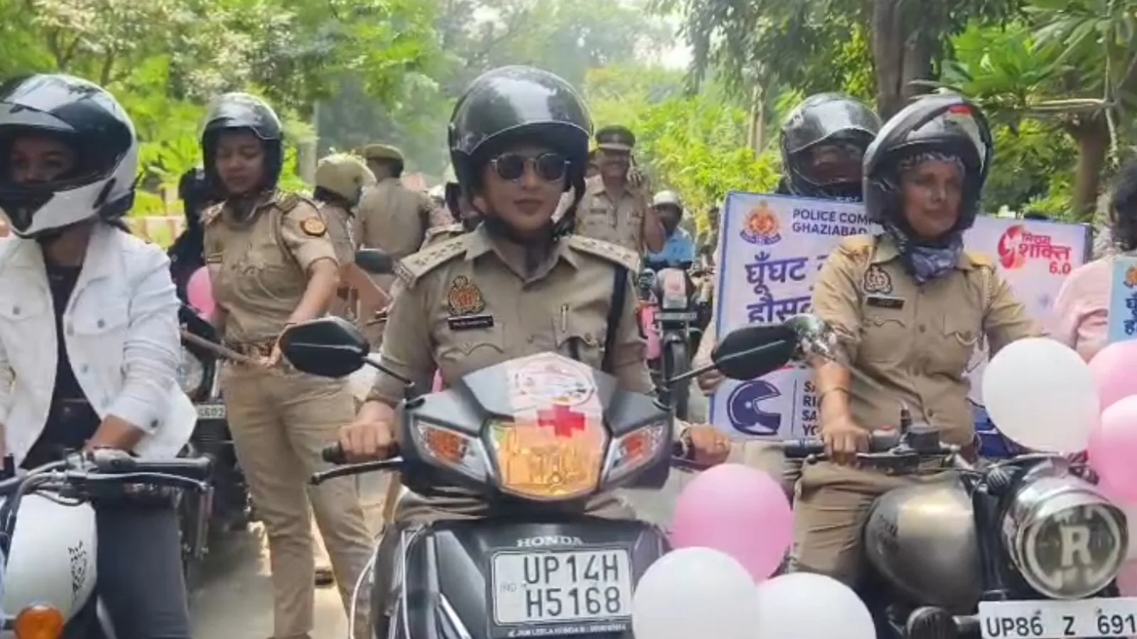 गाजियाबाद रैली में दोपहिया वाहनों पर हेलमेट पहने महिला पुलिसकर्मी और नागरिक प्रतिभागी