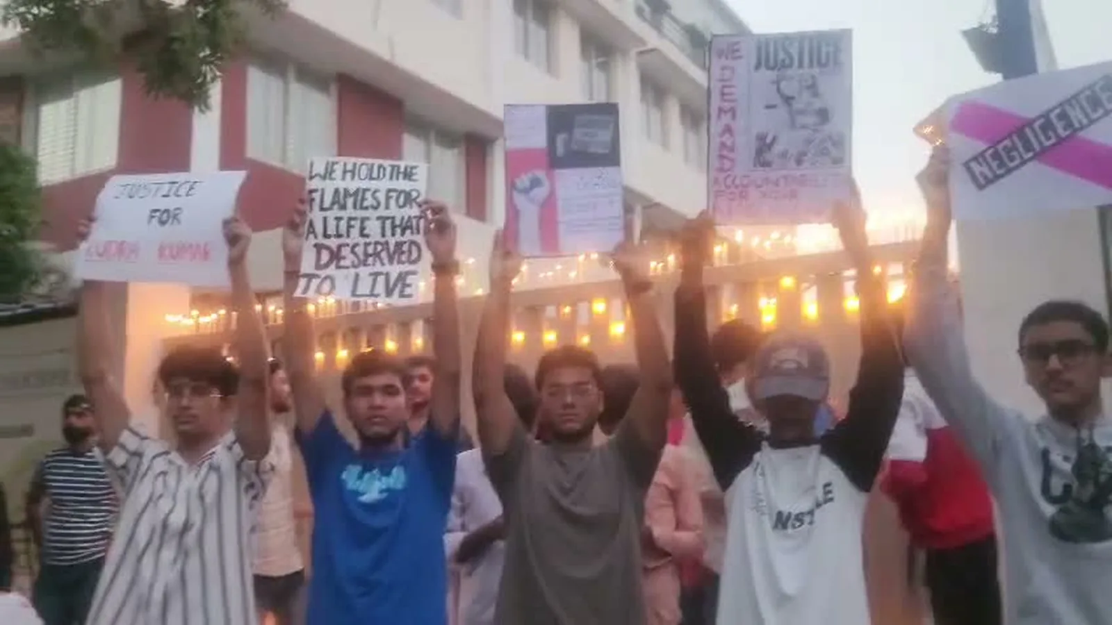 People outside the school hold candles and placards demanding justice