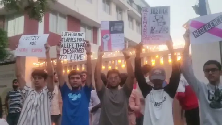 People outside the school hold candles and placards demanding justice