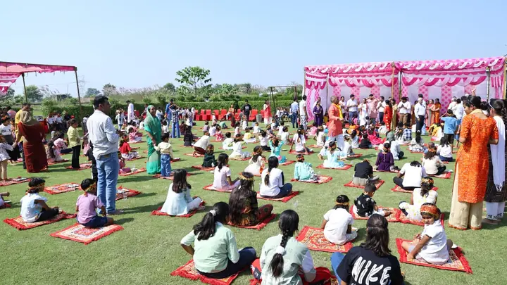 संस्कार उपवन के आयोजन में हरे लॉन पर लाल चटाइयों पर बैठे बच्चे और आसपास उपस्थित वयस्क