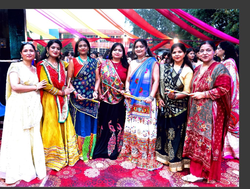 A group in traditional clothing poses with dance sticks at the gathering