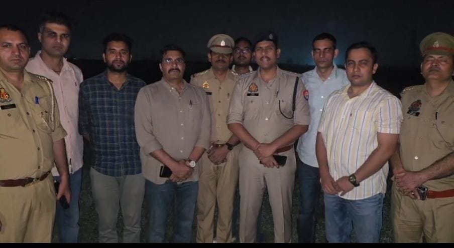 Police personnel and other men pose outdoors at night in a supplied photograph