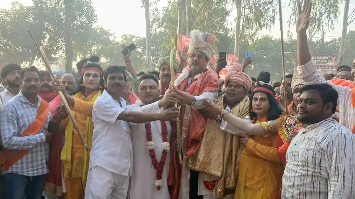 Participants holding a bow beside costumed performers at the Jahangirabad Ramlila gathering