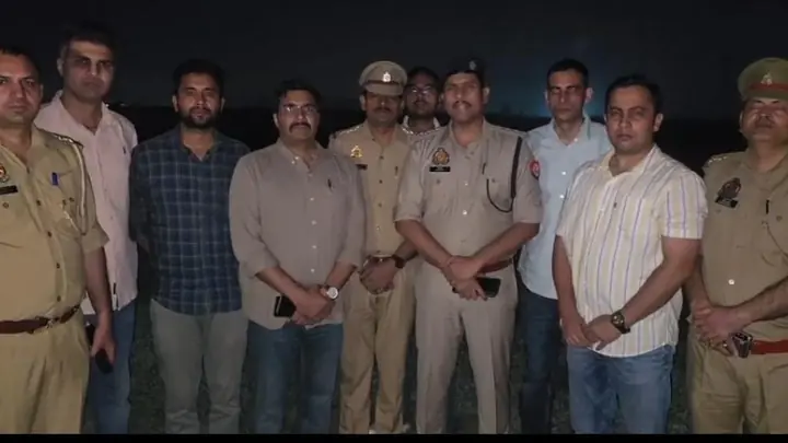 Police personnel and other men pose outdoors at night in a supplied photograph
