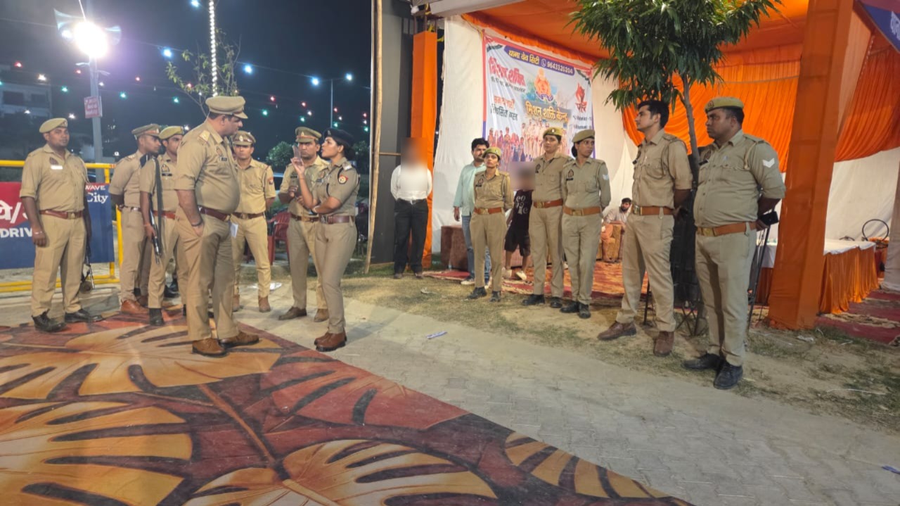नारंगी सफेद पंडाल और बैरिकेड के पास बातचीत करते पुलिस अधिकारी