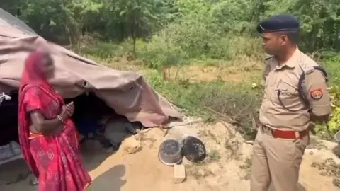 Police officer speaking with a woman outside a makeshift shelter