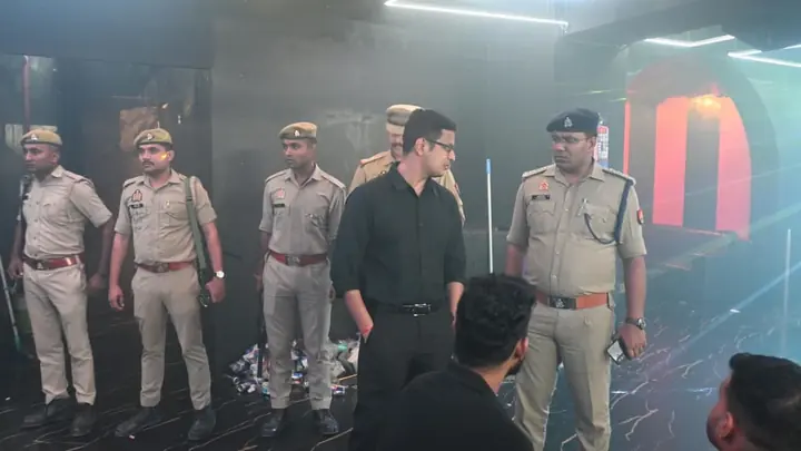 धुंधले प्रकाश वाले प्रतिष्ठान के भीतर पुलिसकर्मी और काले कपड़ों में व्यक्ति