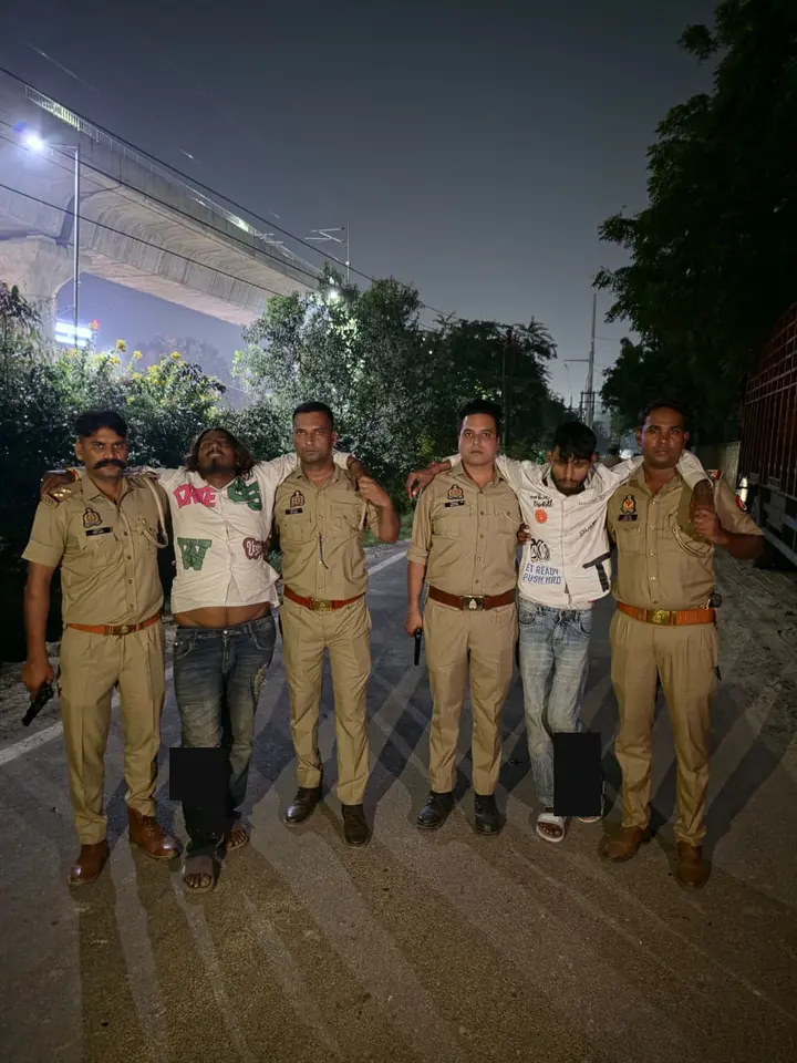 सड़क पर चार पुलिसकर्मियों के साथ दो आरोपी, जिनके पैरों पर संपादकीय मास्क लगाए गए हैं।