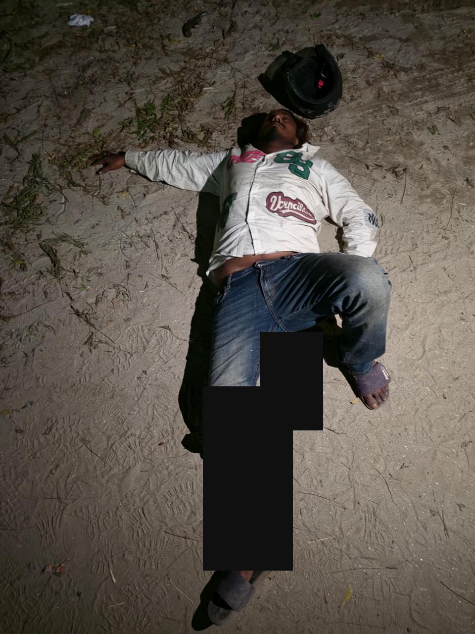 A person on the ground at night; the leg and nearby area are masked.
