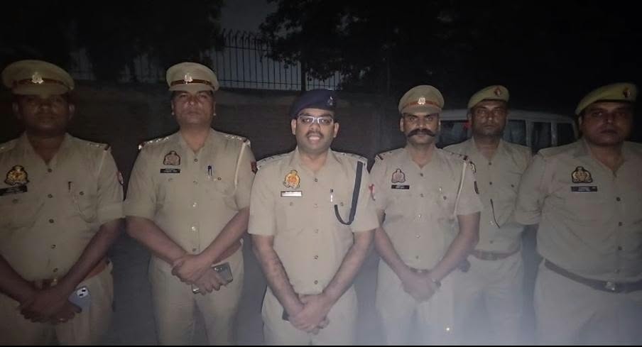 सड़क किनारे रात में पंक्ति में खड़े छह वर्दीधारी पुलिसकर्मी।