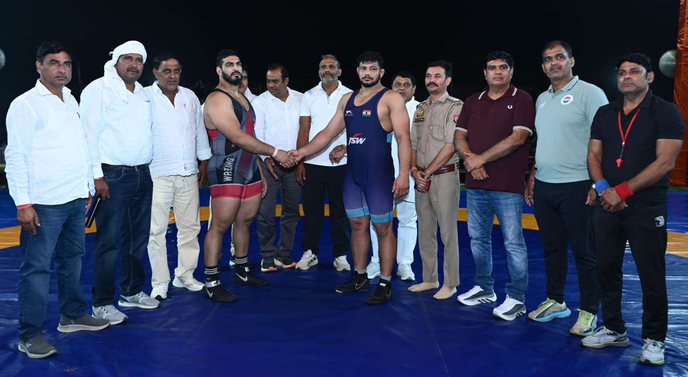 Two wrestlers shaking hands with a group and police officer behind them