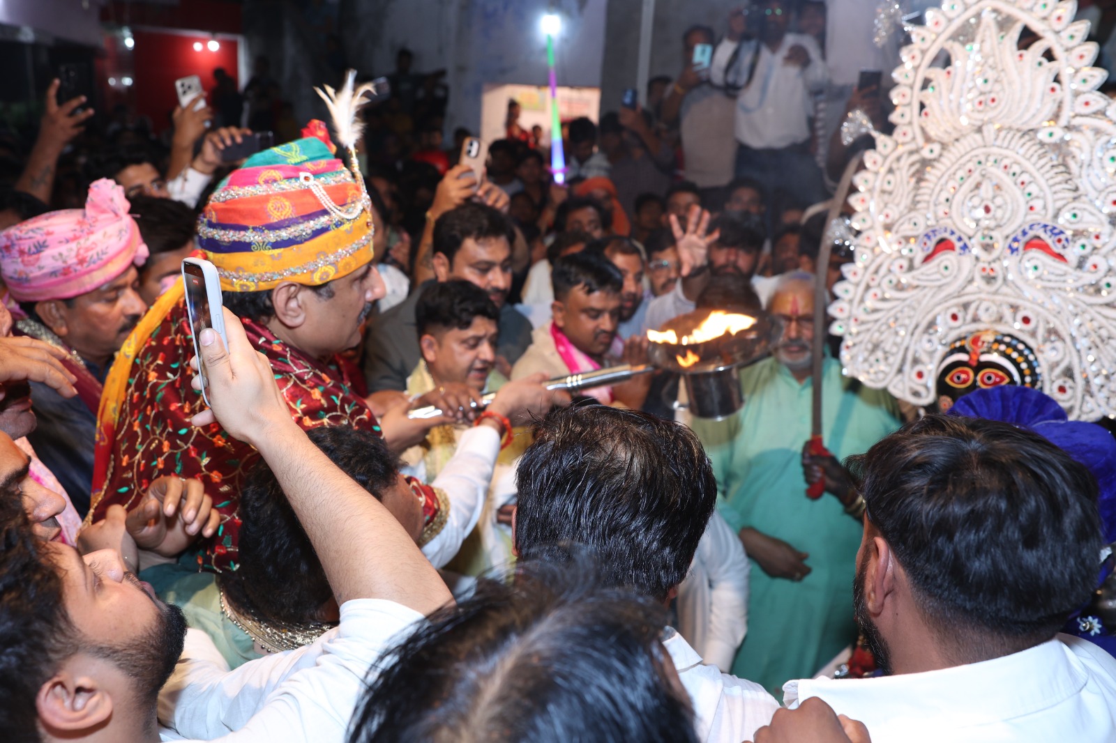 Crowd of devotees, a black-faced Kali-related representation and a flame offering during aarti