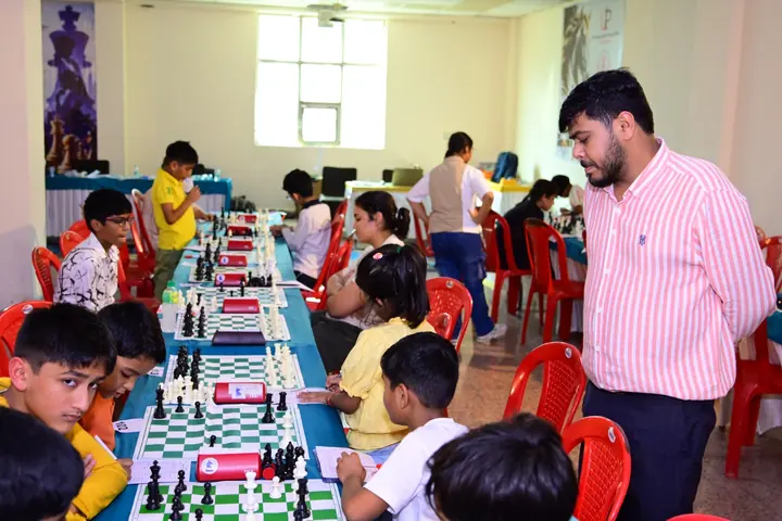 Young participants play at chessboards with clocks and scoresheets.