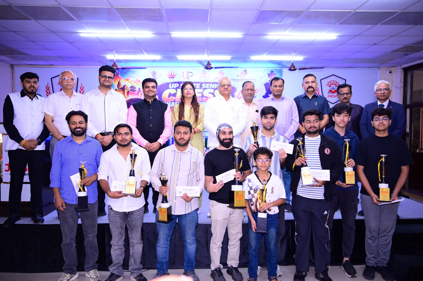 Prize recipients hold trophies at the JMSIT chess championship.