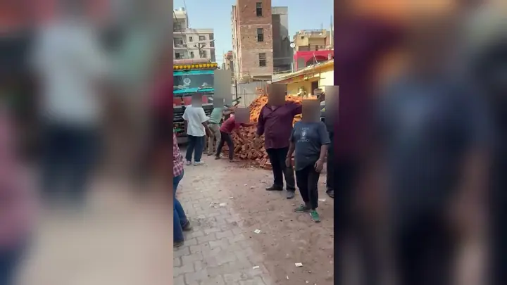 खोड़ा में कथित जमीन विवाद के स्थल पर ईंटों और ट्रक के पास मौजूद लोग